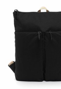 Zaino in tessuto nero con superficie texturizzata, dotato di due tasche frontali con zip e una maniglia superiore per il trasporto. Accenti in beige.