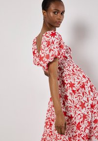 Kurzärmeliges, rot-weißes Blumenkleid mit schmalem Oberteil und fließendem Rock, ausgestattet mit Puffärmeln und einem runden Rückendesign.