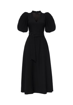 Czarna sukienka z bufiastymi krótkimi rękawami, dekoltem w kształcie litery V i paskiem w talii. Ma dopasowaną górę i rozkloszowany dół. Zamek błyskawiczny z tyłu.