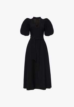 Czarna sukienka z bufiastymi krótkimi rękawami, dekoltem w kształcie litery V i paskiem w talii. Ma dopasowaną górę i rozkloszowany dół. Zamek błyskawiczny z tyłu.