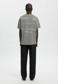 Hall hallist puuvillast t-särk, millel on valgete tähtedega tagaküljel graafika. Lõdvestunud lõige, ümmargune kaelus, lühikesed varrukad, paaritud mustade laia säärega pükstega.