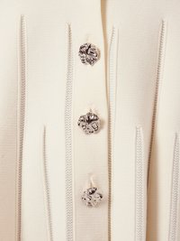 Cardigan bej cu cusături verticale și patru butoane metalice cu un design texturat, floral, fabricat dintr-un material moale, tricotat.