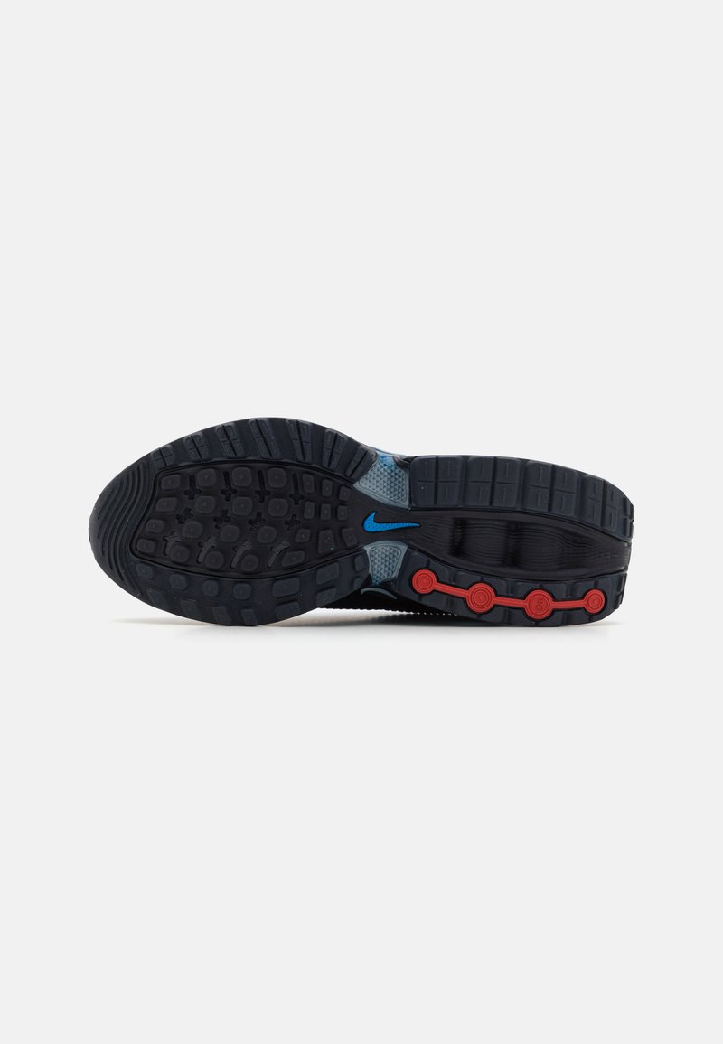 Semelle de chaussure de sport noire avec caoutchouc texturé, accents bleus, détails circulaires rouges et rainures profondes pour une meilleure adhérence.