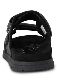 Svart sandal med texturerad konstläderövre, justerbara remmar, en vadderad svart mockainnersula och en hållbar gummisula.