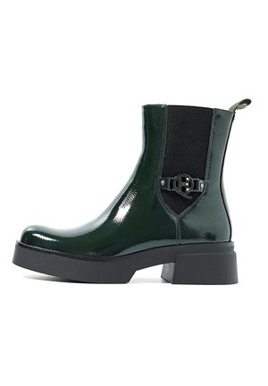 Stivale alla caviglia in vernice verde con pannelli elastici laterali, punta rotonda, suola platform nera e dettaglio decorativo con fibbia in metallo.