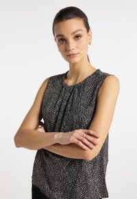 Top negru fără mâneci, cu un model texturat de stropi albi, având detalii adunate la guler și o croială lejeră.