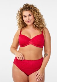 Czerwony komplet bielizny, w skład którego wchodzi koronkowy biustonosz z falistymi krawędziami oraz majtki o wysokim stanie z kwiatowymi wzorami. Miękki, elastyczny materiał, bezszwowy design.