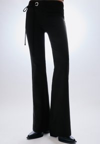 Fekete, bővülő szárú nadrág magas derékrésszel, fém szemmel és megkötővel díszítve. Sima, texturált anyagból készült.