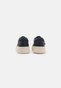Mørkeblå lædersneakers med en glat overflade, der har en beige gummisål og diskrete syninger. Rund form, minimalistisk design.