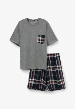 Ensemble de pyjama composé d'un t-shirt gris à manches courtes avec une poche poitrine à carreaux, associé à un short à carreaux bleu marine, rouge et blanc, sur fond blanc.