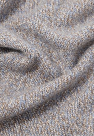 Tissu tricoté doux en gros plan avec des fils beige et bleu clair, montrant une texture fine et de douces plis.