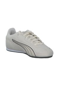 Lys grå sneaker lavet af ruskind med en tekstureret overdel, der har flade snørebånd, sorte striber og en sort gummisål.