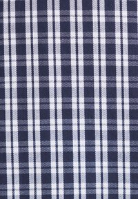Tissu à carreaux bleu et blanc avec un motif tissé de tartan composé de rayures verticales et horizontales alternées, épaisses et fines.