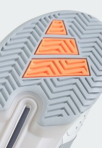 Podešev boty v šedé gumě má texturovaný cik-cak vzor, se světlými oranžovými trojúhelníkovými akcenty uprostřed pro trakci a uchopení.