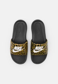 Melni slaidi apavi ar leoparda rakstu siksnu, ar baltu Nike logotipu. Pēdas vieta ir ar rievotu tekstūru, lai nodrošinātu paaugstinātu saķeri un komfortu.