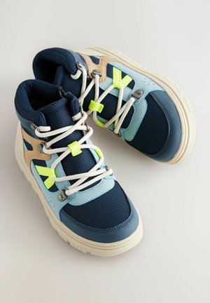 Hochschuh-Sneaker mit einem Obermaterial aus navyfarbenem Mesh, hellblauen Akzenten, beigen Überzügen und reflektierenden Neon-Details. Dicke weiße Schnürsenkel und Gummisohle.