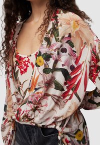 Květinový otevřený kimono, lehká tkanina s živými barevnými květinami, včetně červených, růžových a žlutých akcentů, svázané v pase.