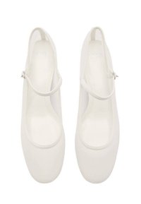 Ballerines blanches à bout rond, fabriquées en tissu doux. Elles possèdent une fine bride à la cheville et une surface lisse sans embellissements supplémentaires.