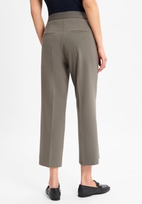 Grijze cropped broeken met een soepele textuur, elastische tailleband en twee achterzakken. G gedragen met zwarte instappers, met een eenvoudig ontwerp.