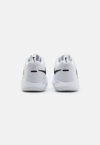 Hvide sportssko med sorte accenter, der har en glat tekstur, afrundet form og polstret sål. Nike-logoet på hælen.
