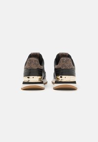 Sneaker neri e marroni con tacco a motivo, dettagli metallici dorati e un design a suola stratificata che mette in mostra una combinazione di colori bianca e marrone.