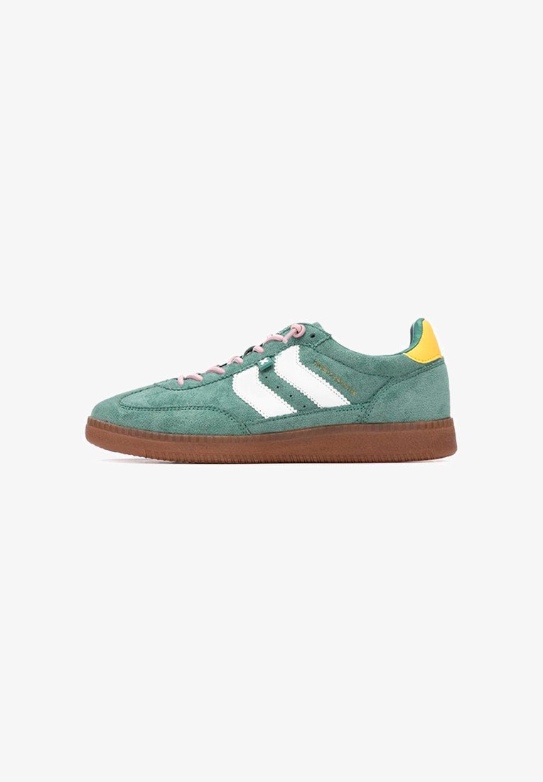 Zapatillas de ante verdes con rayas blancas, cordones rosas y un acento amarillo en el talón. Presenta una suela de goma marrón y una superficie texturizada.