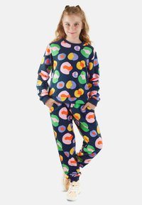 Conjunto de sudadera y pantalones de chándal con un colorido estampado que presenta grandes manchas abstractas en rosa, naranja, verde y morado sobre un fondo marino.