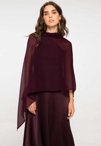 Capa burdeos hecha de tela transparente, cayendo elegantemente sobre un vestido burdeos sólido. Presenta un escote alto y una silueta fluida.