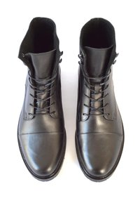 Botas de cuero negro con cordones, acabado suave, diseño de tobillo alto y punta redondeada. Presentan ojales metálicos y un forro interno suave.