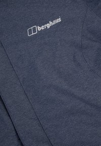 Mörkblå strukturerad tyg med "berghaus"-logotypen tryckt i vitt nära en söm.