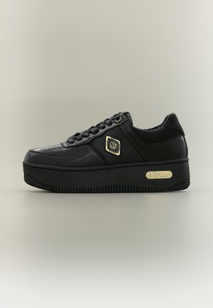 Μαύρο platform sneaker με κορδόνια, χρυσό εξαγωνικό λογότυπο στο πλάι και χρυστή ετικέτα της μάρκας στην παχιά σόλα, σε ουδέτερο φόντο.