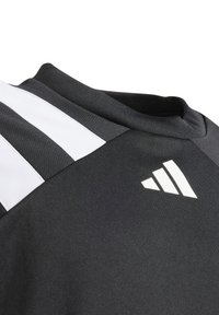 Svart idrottströja med rund hals, vit tre-stripes design på axeln och en vit logotyp på bröstet. Slät tygtextur.