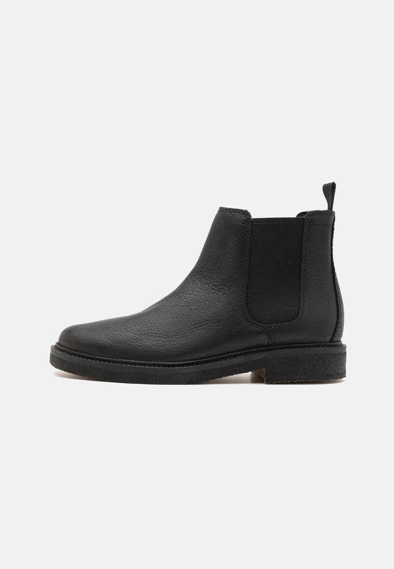 Botín Chelsea de cuero negro con un acabado texturizado, paneles laterales elásticos y una tira de agarre, que presenta una suela de goma baja y plana.