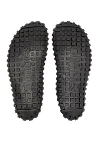 Black rubber shoe soles with textured surfaces, featuring square and rectangular patterns, designed for grip and traction.
