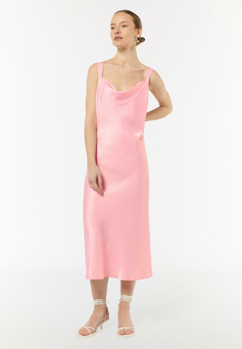 Różowa satynowa sukienka z kołnierzem, szerokimi ramiączkami i długością do kolan. Gładka tekstura i subtelny połysk; w komplecie z beżowymi sandałami na obcasie.