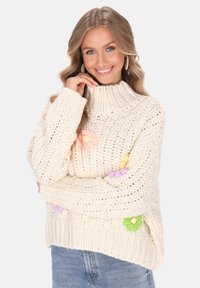 Cremfarbener Pullover aus Strick mit hohem Kragen, der aus pastellfarbenen Blumenapplikationen in Rosa, Gelb, Lila und Grün besteht. Strukturierter, grob gestrickter Stil.