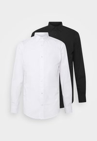 Dos camisas de manga larga, una blanca y otra negra, con cuello de punta y cierre de botones, hechas de tela suave.
