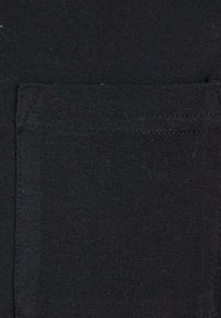 Prim-plan al unui buzunar cusut din material textil negru cu cusături vizibile pe un articol de îmbrăcăminte negru.