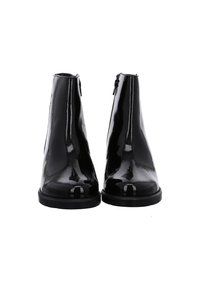 Een paar zwarte glanzende enkellaarsjes met ritsen aan de zijkant, ronde neuzen en platte rubberen zolen, gezien van voren op een witte achtergrond.