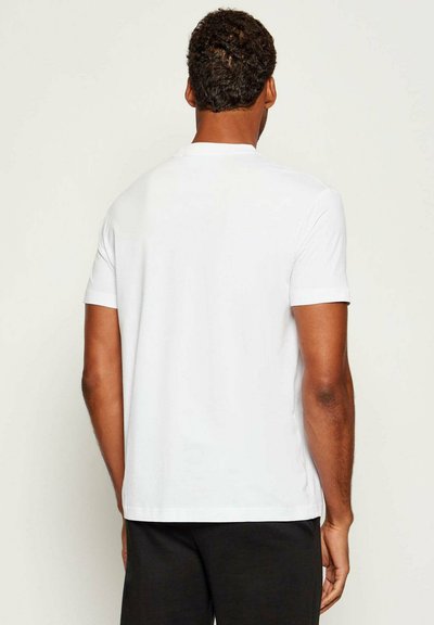 T-shirt bianco a maniche corte con collo rotondo, in morbido cotone, con orlo dritto in fondo, privo di marchi o elementi decorativi visibili.