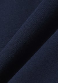 Gros plan d'un tissu bleu marine foncé avec une texture fine en tricot et des plis visibles.