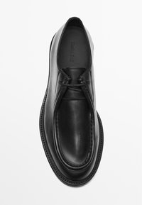 Schwarzer Lederschuh mit glatter Oberfläche, runder Zehenpartie und dezenten Nähten. Verfügt über einen elastischen Einstieg für ein einfaches Anziehen.