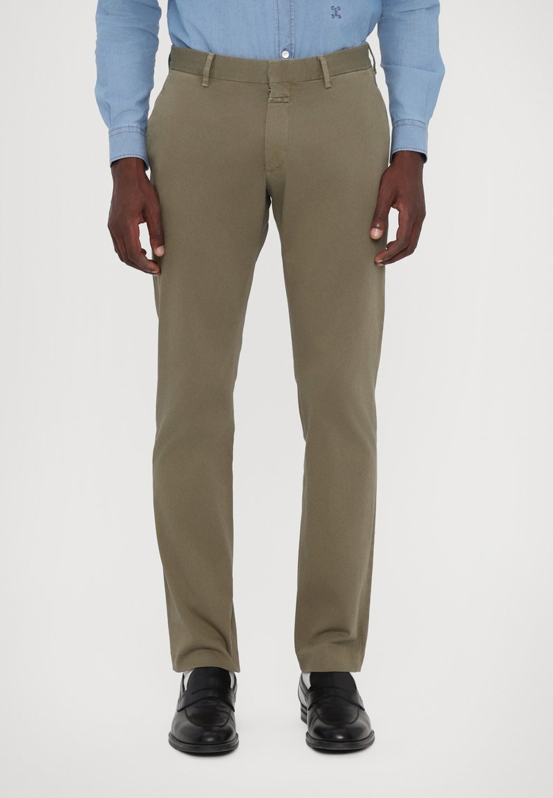 Chinos vert olive avec une texture lisse, design à jambe droite et poches avant, associés à des chaussures habillées noires.