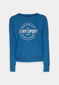 Blue sweatshirt with a round neckline and raglan sleeves. Features silver DKNY Sport logo centered on the front. Soft fabric with ribbed cuffs.