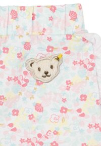 Tejido de color azul claro con un patrón floral, con flores en tonos rosa y amarillo; presenta un aplique texturizado de la cara de un oso con un acento amarillo.