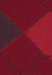 Primo piano di un motivo argyle a maglia con colori rosso, viola scuro e rosa, e linee cucite di verde scuro su tessuto.