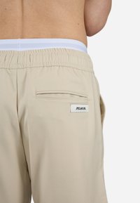 Beige shorts med en elastisk hvid talje og en baglomme med et lille sort mærke. Glat stof med en skræddersyet pasform.