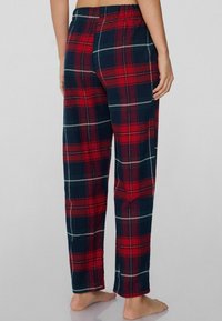 Geruite pyjamabroek in donkerblauw, rood en groen met een elastische tailleband en een ontspannen pasvorm. Zachte katoenen stof met zichtbare patroonlijnen.