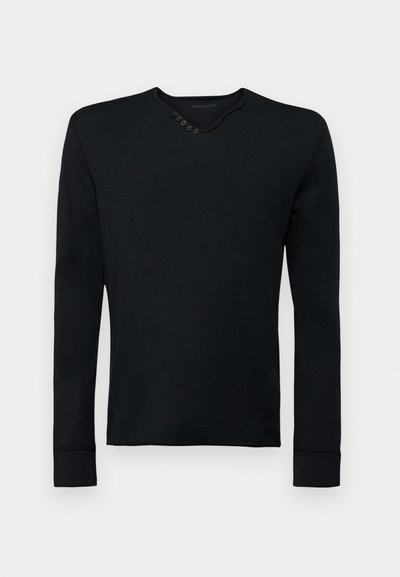 Melna garo piedurkņu krekls, kas izgatavots no mīkstas auduma, ar apaļu kakla izgriezumu un pieciem dekoratīviem pogām kreisajā plecā, kā arī ribotām piedurknēm.