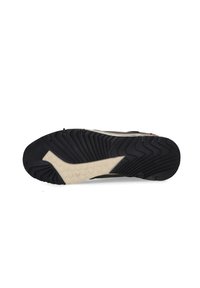 Schwarz-weißes Sport-Schuhsohle mit einem strukturierten Muster, das einen cremefarbenen Akzent aufweist. Das Design enthält ausgeprägte Rillen und ein hexagonales Detail.